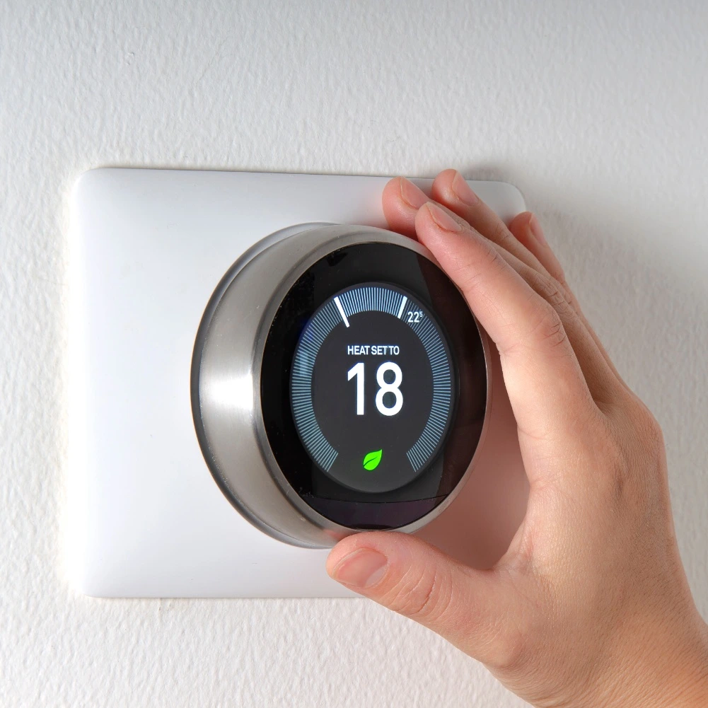 Hand adjusting a smart thermostat, highlighting the need for AC thermostat repair.